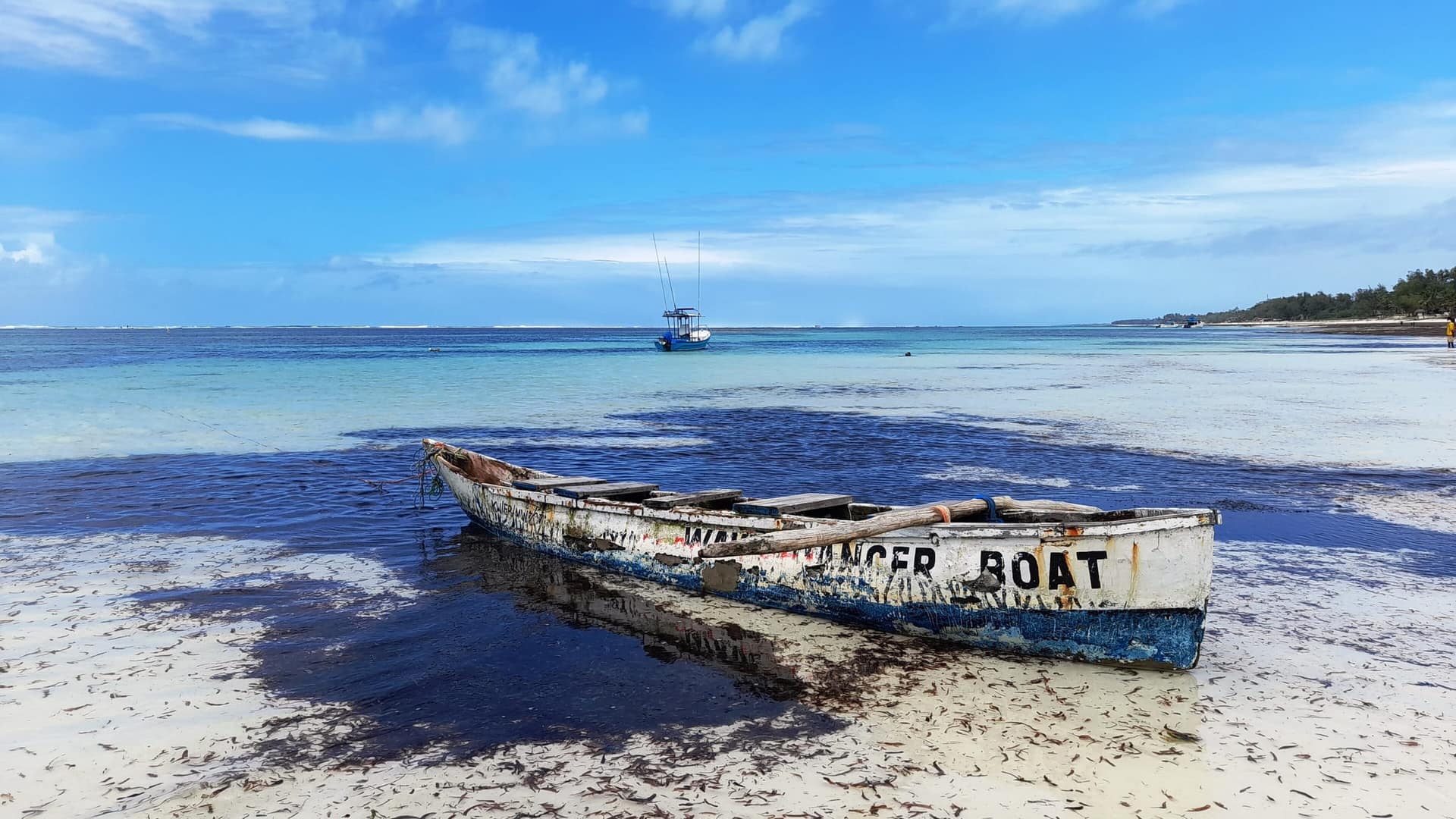 Una barca di legno ferma in acque turchesi e basse sulla costa sud del Kenya