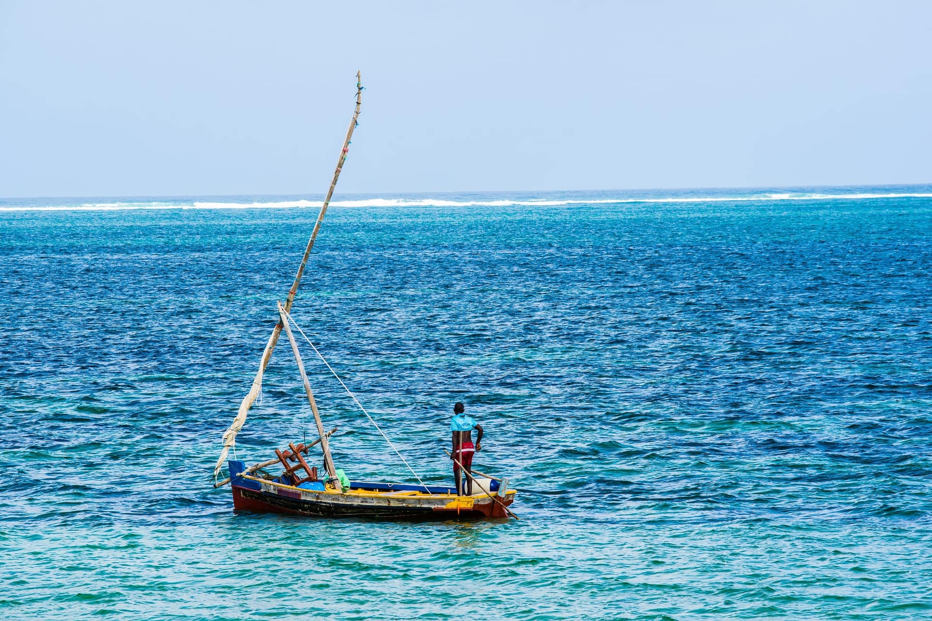 Un pescador en su pequeña barca de vela en las aguas de Mombasa